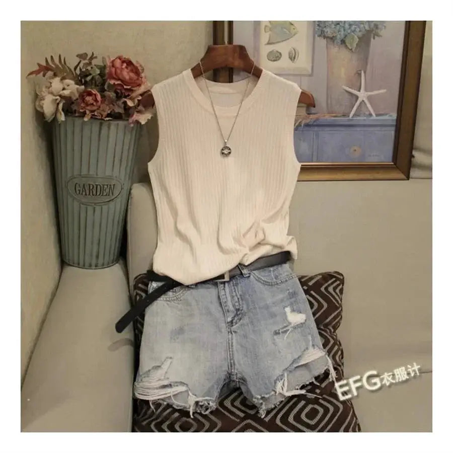 Simples Market cream ribbed sleeveless knit top with O-neck, paired with distressed light-wash denim shorts and necklace.