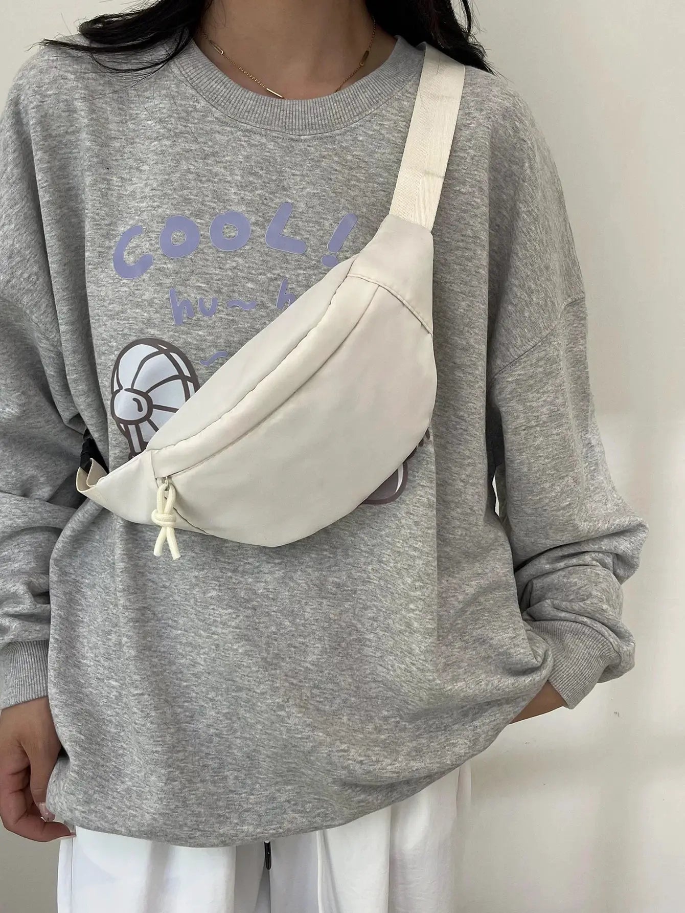 Cream fanny pack worn as a crossbody bag with a beige strap.