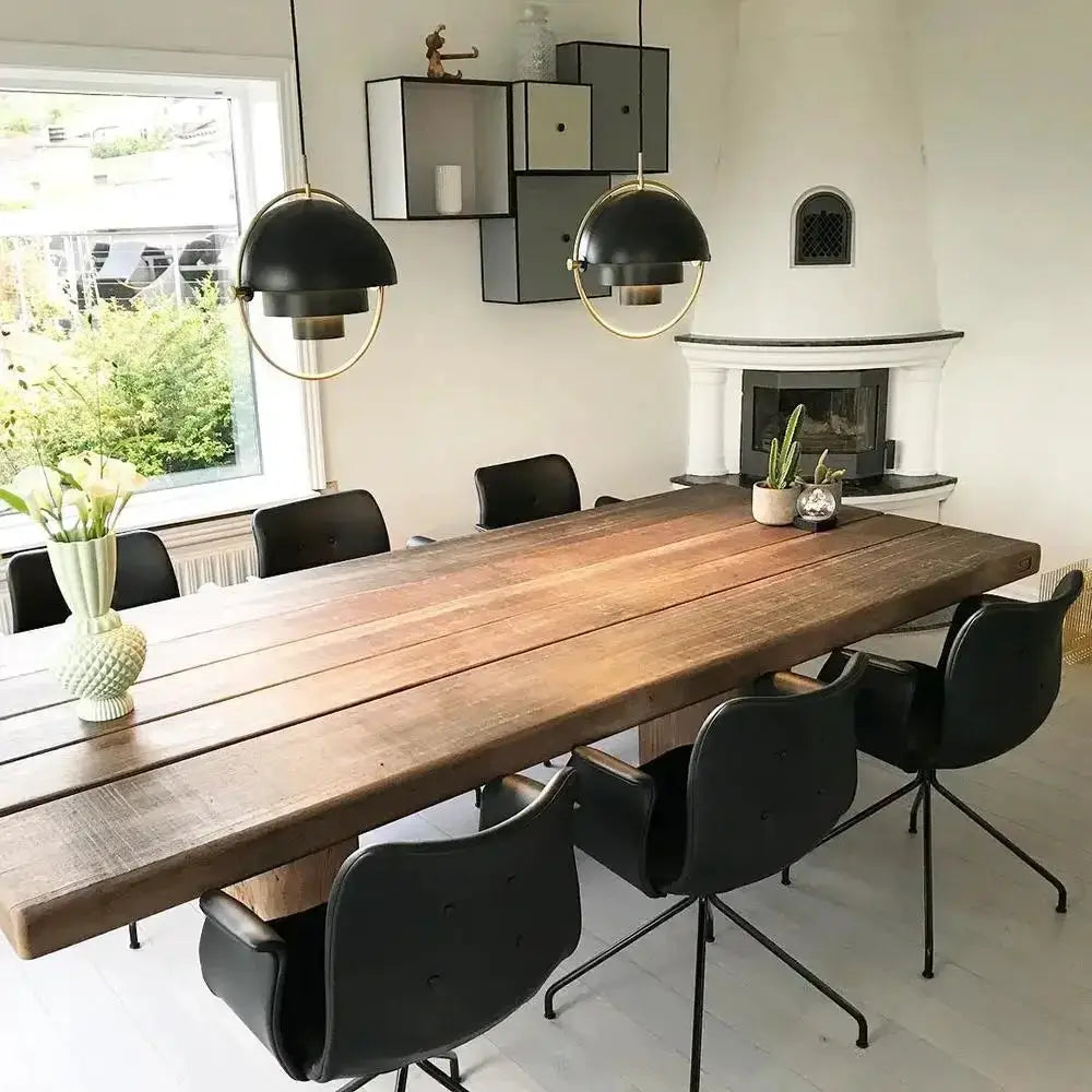 Pendant light by Simples Market; black iron dome with gold ring hanging over a wooden dining table