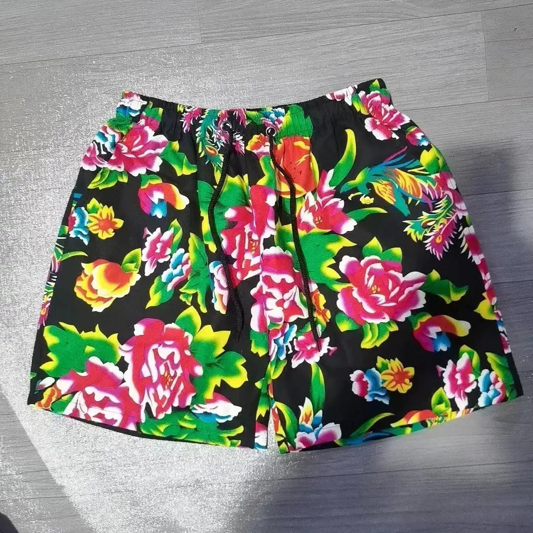 Men's swim shorts with vibrant tropical floral print on black, drawstring waist.