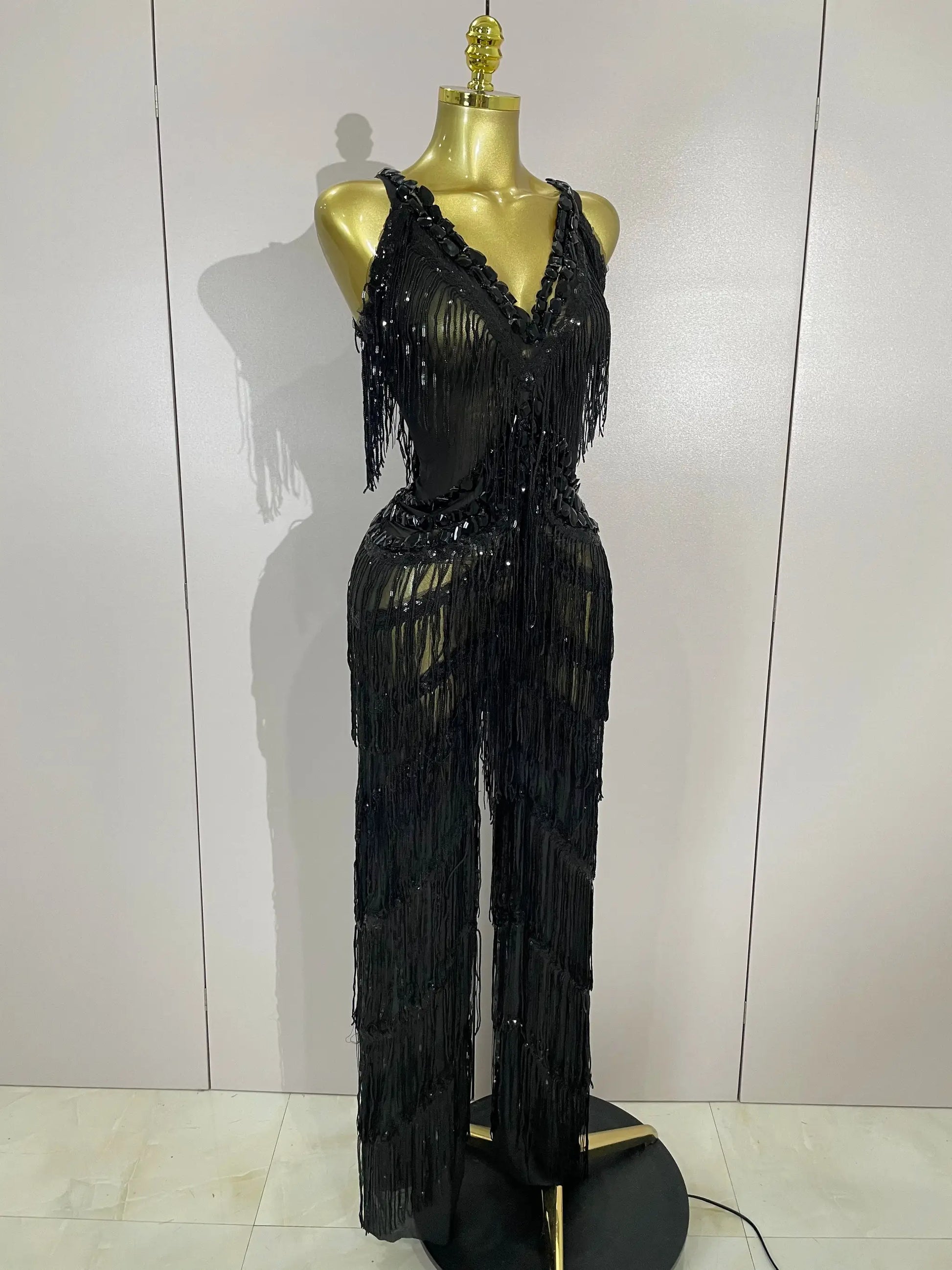 Sparkly black sequined fringe jumpsuit on mannequin, deep V-neck, long rhinestone fringe for stage performance
