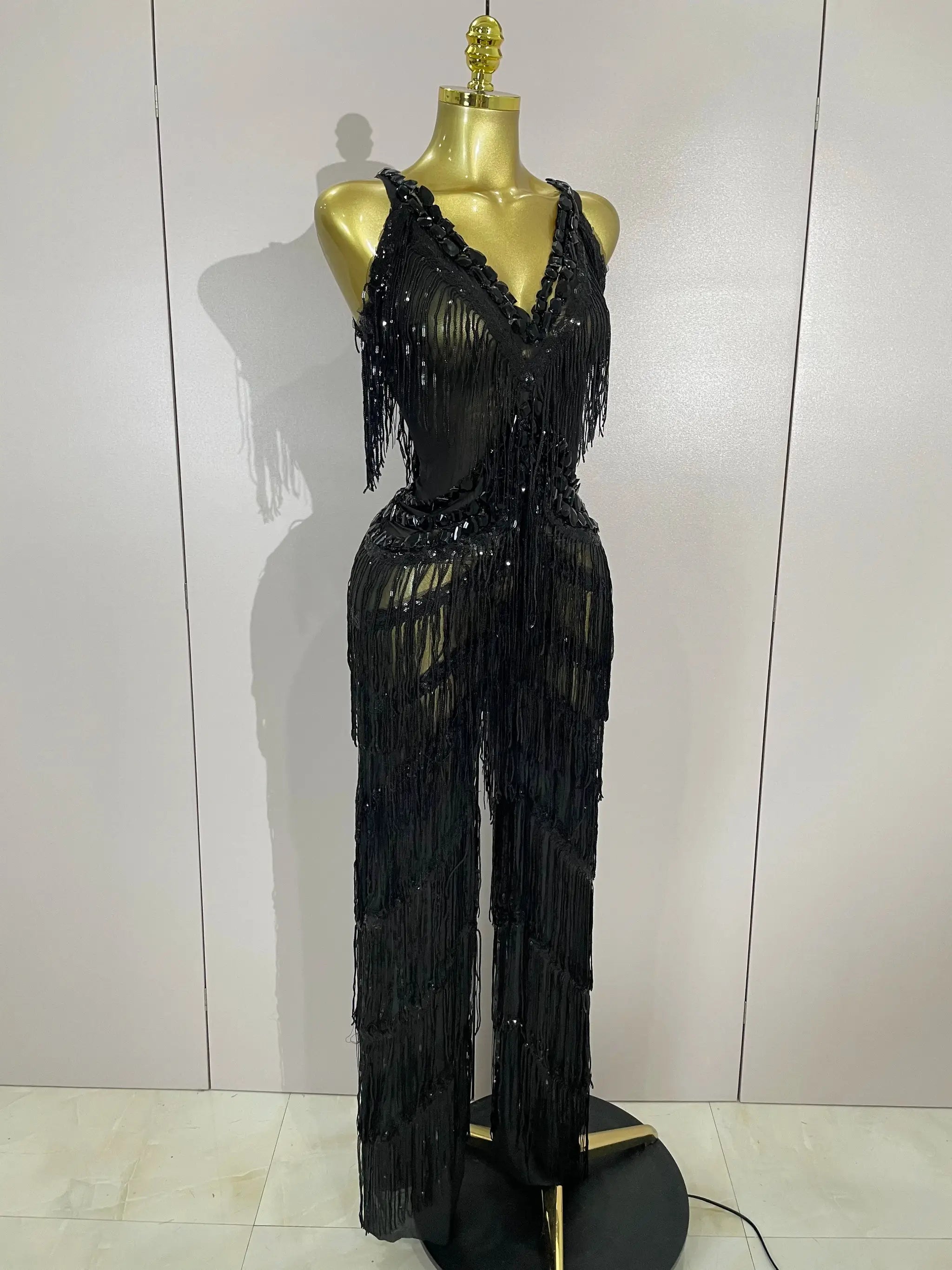 Sparkly black sequined fringe jumpsuit on mannequin, deep V-neck, long rhinestone fringe for stage performance