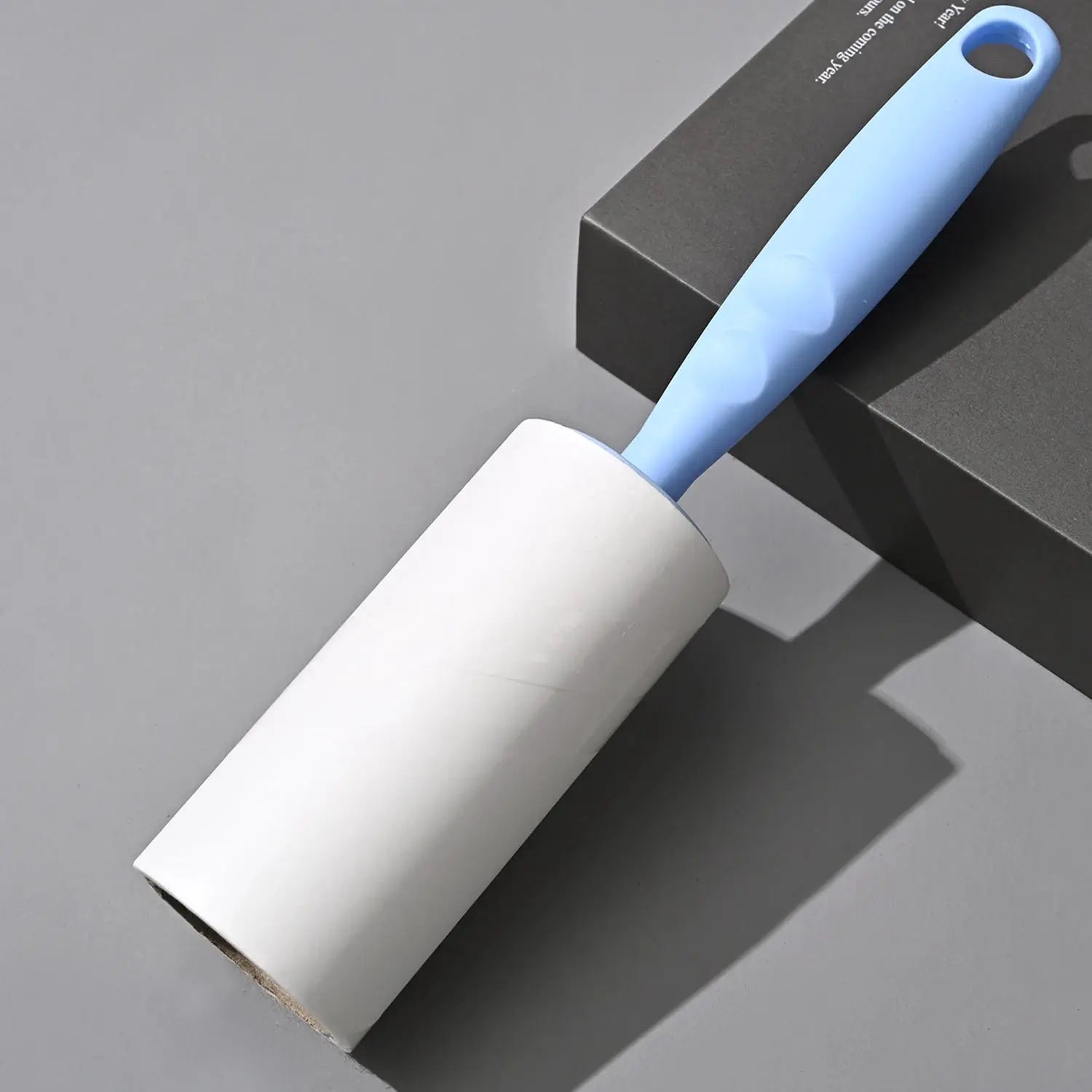 Lint roller with blue ergonomic handle and white replaceable roll for removing pet hair and dust from clothes and sofa.