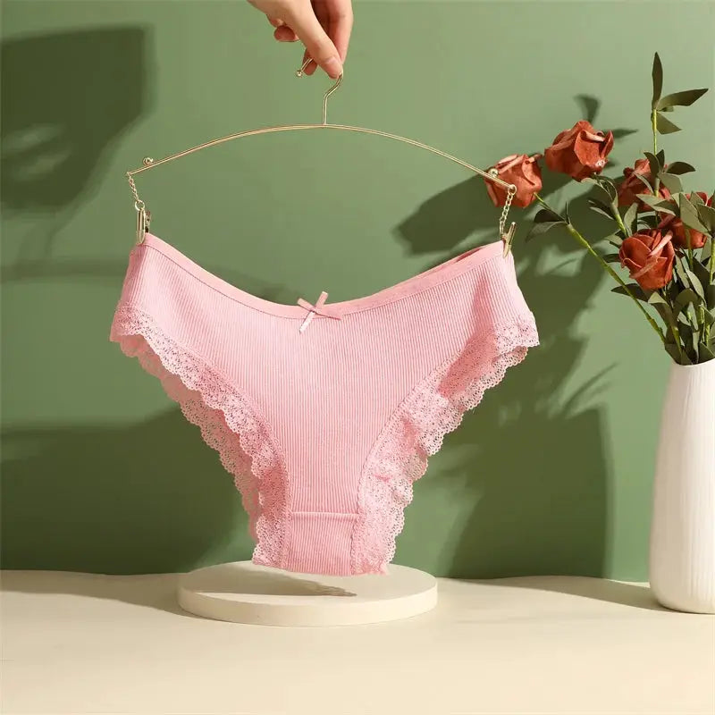 Pink cotton panties with lace trim and bow, low-rise Brazilian style on a hanger.