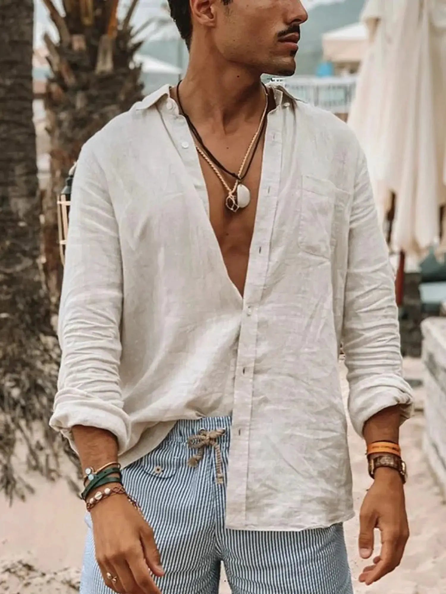 Men's beige linen long-sleeve shirt with open collar, outdoors, paired with blue striped pants