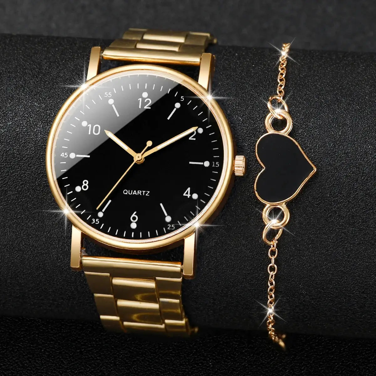 Gold-tone women's quartz watch with black Arabic dial; includes matching gold heart-charm bracelet (2-piece set)