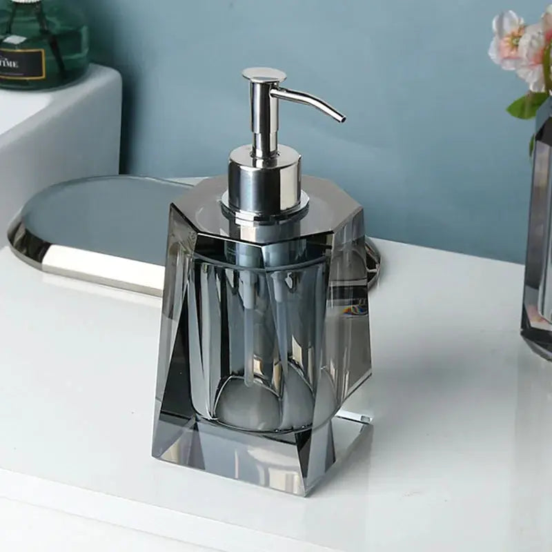 Glass lotion dispenser with clear crystal facets and chrome pump on bathroom counter