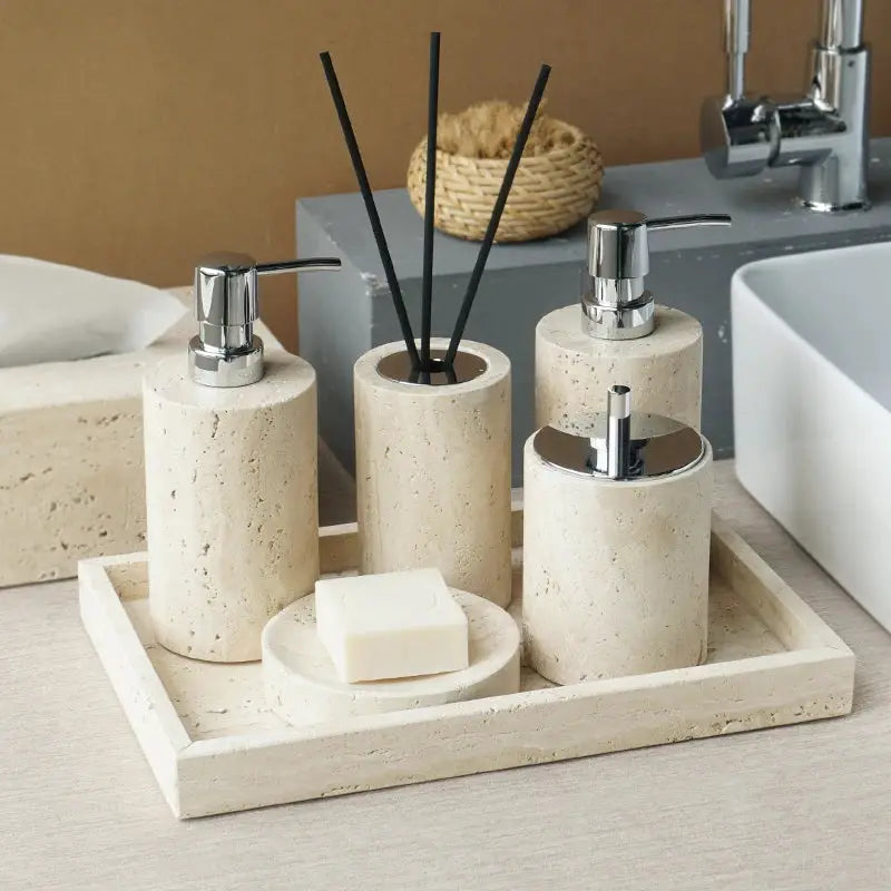 Beige travertine bathroom accessories set with three soap dispensers, reed diffuser, soap dish and vanity tray