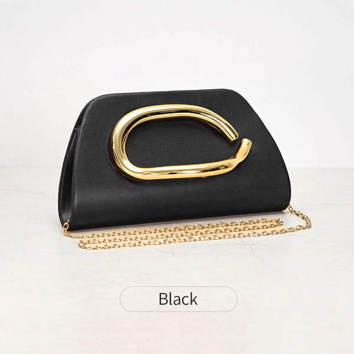 Box clutch handbag in black with a bold gold buckle and gold chain strap