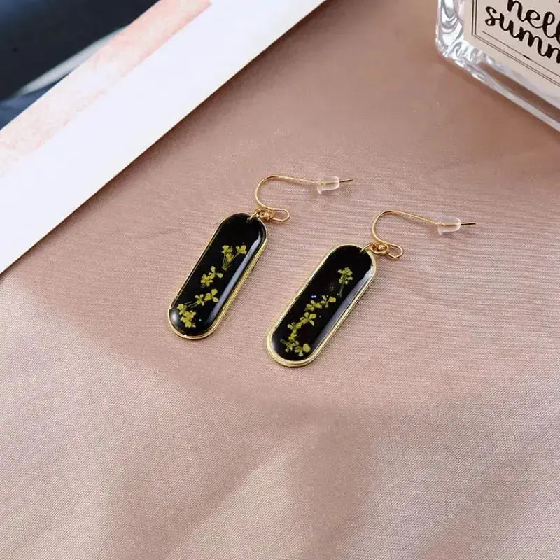 Pressed flower epoxy resin earrings with black rectangular drops and gold-tone frame, pair