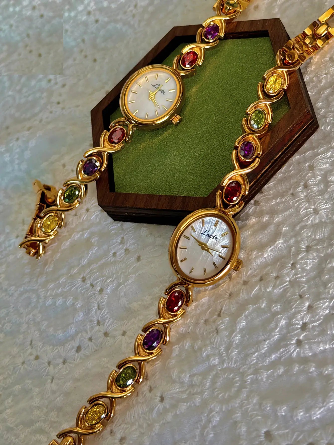 Gold-tone luxury women's watch with colorful tourmalines and diamonds on a bracelet, oval mother-of-pearl dial.
