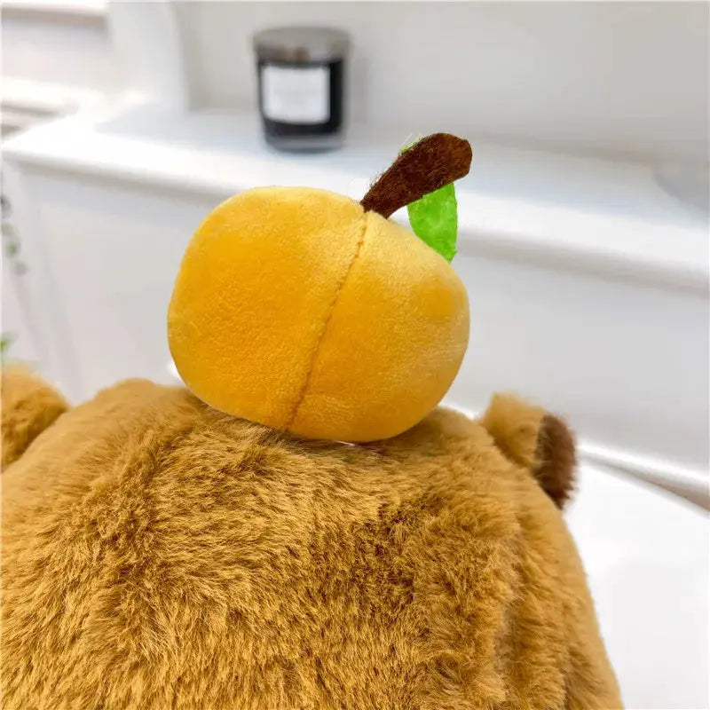 Capybara plush backpack in brown fur with a yellow peach accessory on top