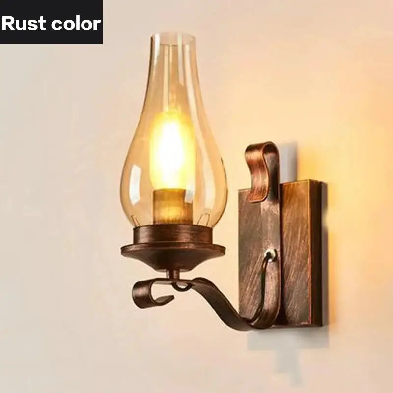 Rust-color wrought-iron wall sconce with curved arm and glass shade