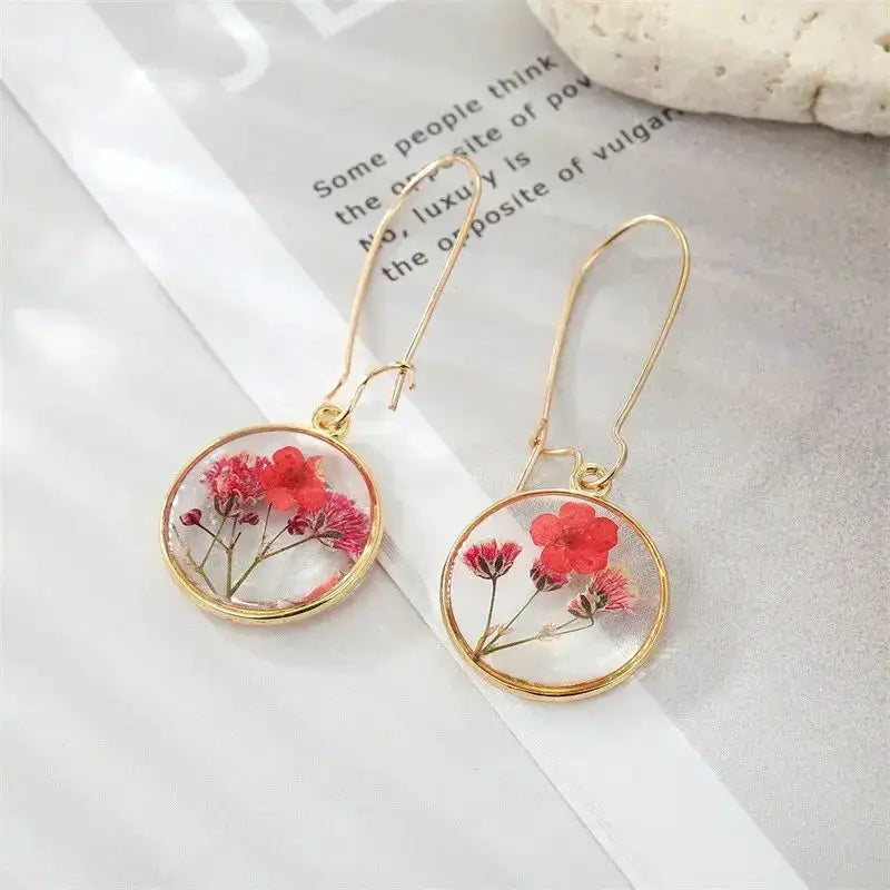 Natural flower dangle earrings pair, gold-tone circular epoxy resin frames with red pressed blossoms