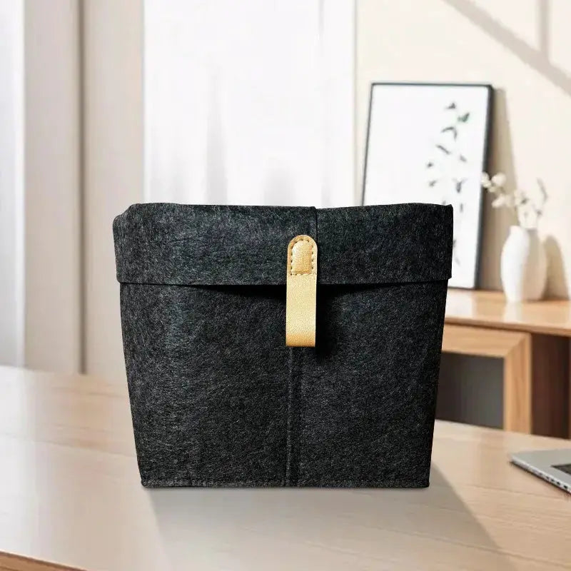 Felt storage basket with lid and tan leather strap, dark gray, for home office organization.