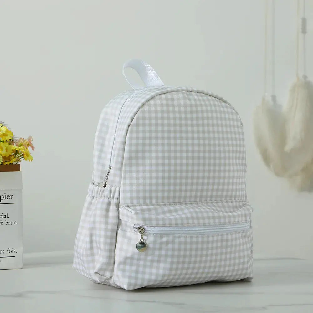 Toddler backpack in white-beige gingham with front zip pocket and white top handle.