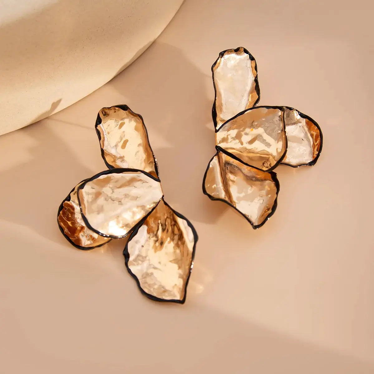 Pair of metal irregular pleated petal earrings with gold-toned hammered petals and black edges