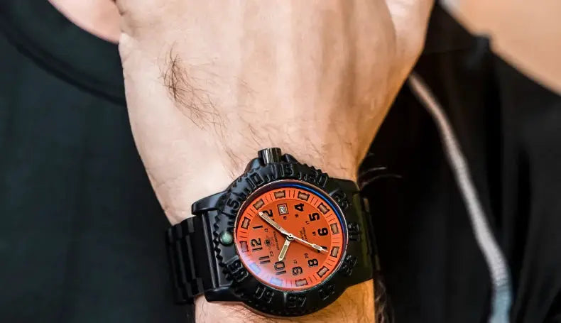 Men's military-style wristwatch with orange dial, black bezel, and black metal strap