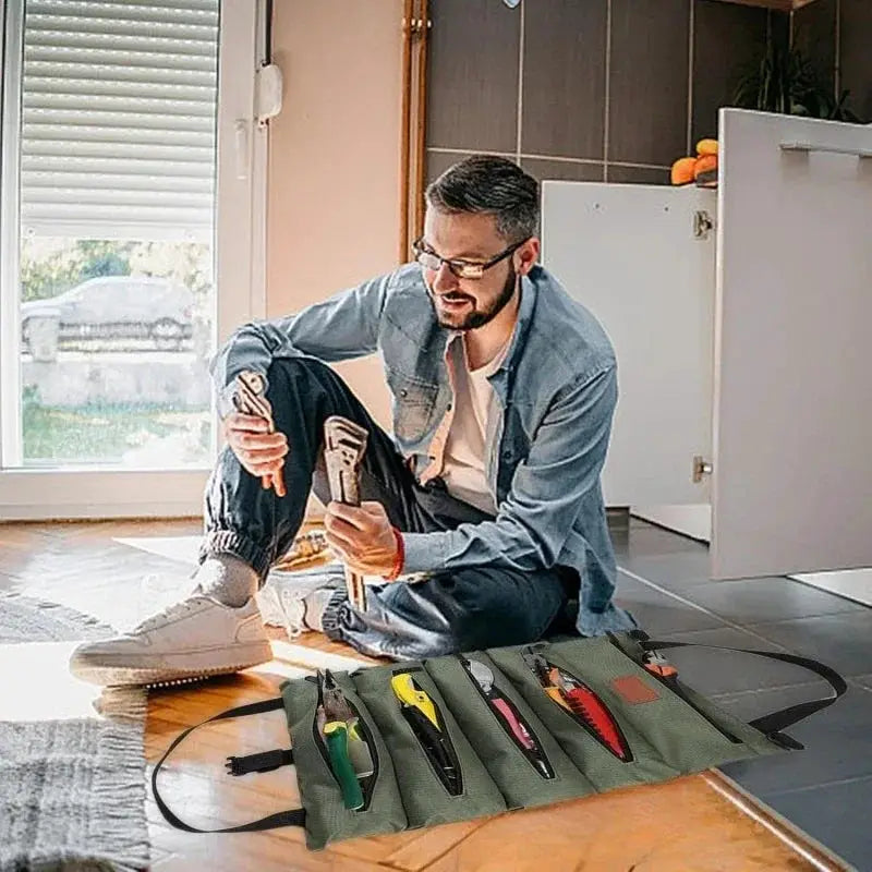 Roll-up tool bag in olive green with five pockets, opened to hold pliers, screwdrivers and other hand tools.