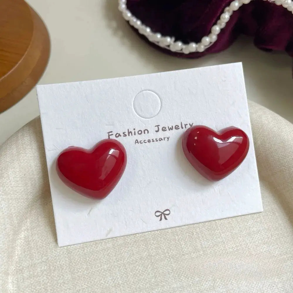 Red heart-shaped stud earrings, two-piece set displayed on white card