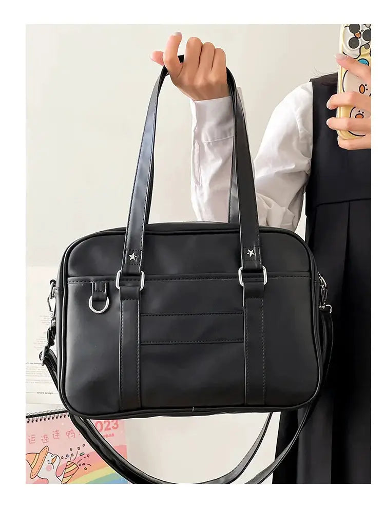 Japanese Style JK bag in black PU leather with dual top handles, crossbody strap, silver hardware, and front pockets.