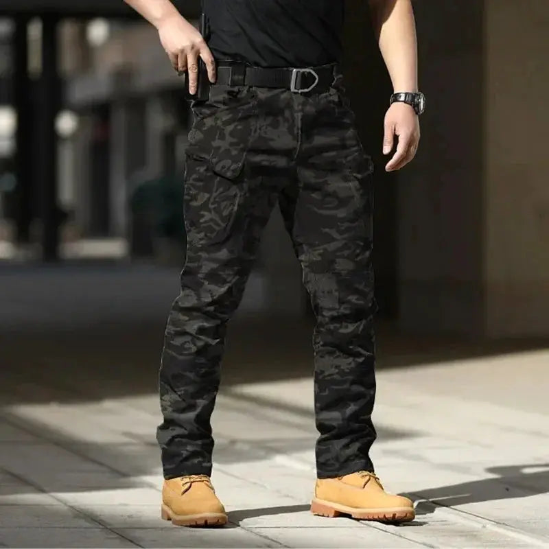 Mens waterproof camouflage cargo pants with multiple pockets and belt, shown with tan boots.