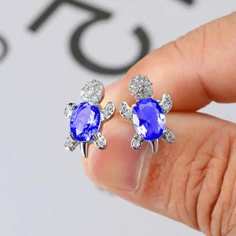 Silver-plated turtle-shaped earrings with blue oval glass stones and clear crystal accents