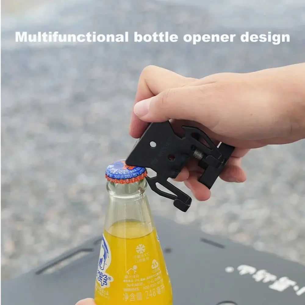 Multifunctional camping bottle opener and gas canister hook in black metal, clamped around a bottle neck.