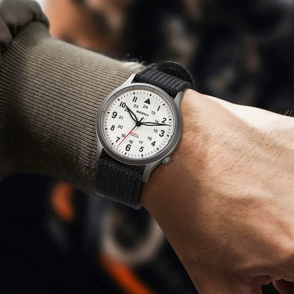 BERNY titanium field watch for men on a wrist with a black fabric strap and white dial