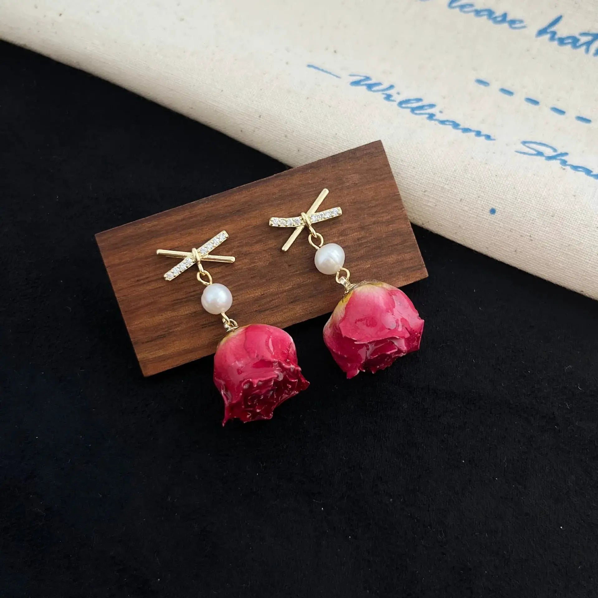 Pair of red rose epoxy resin drop earrings with gold-tone crystal-cross accents and pearl beads