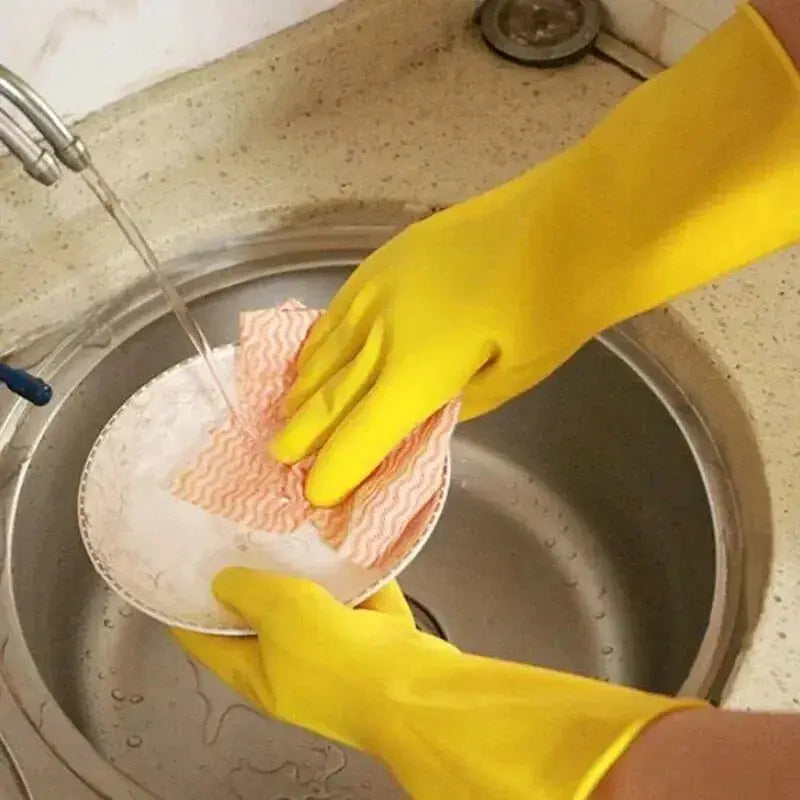 Latex dishwashing gloves, yellow, cleaning a bowl with a pink striped cloth under running water in a kitchen sink