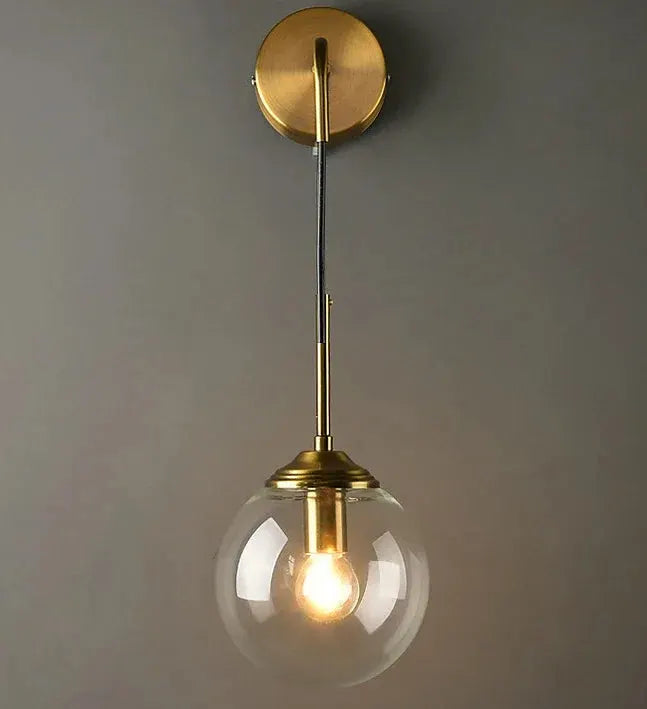 Modern glass wall lamp by Simples Market with brass finish and clear globe