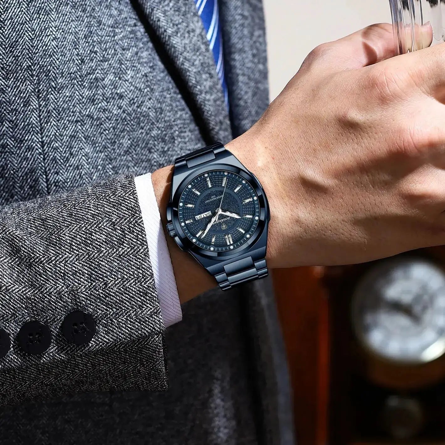 POEDAGAR sport men's stainless steel wristwatch with date window, worn on a gray herringbone suit