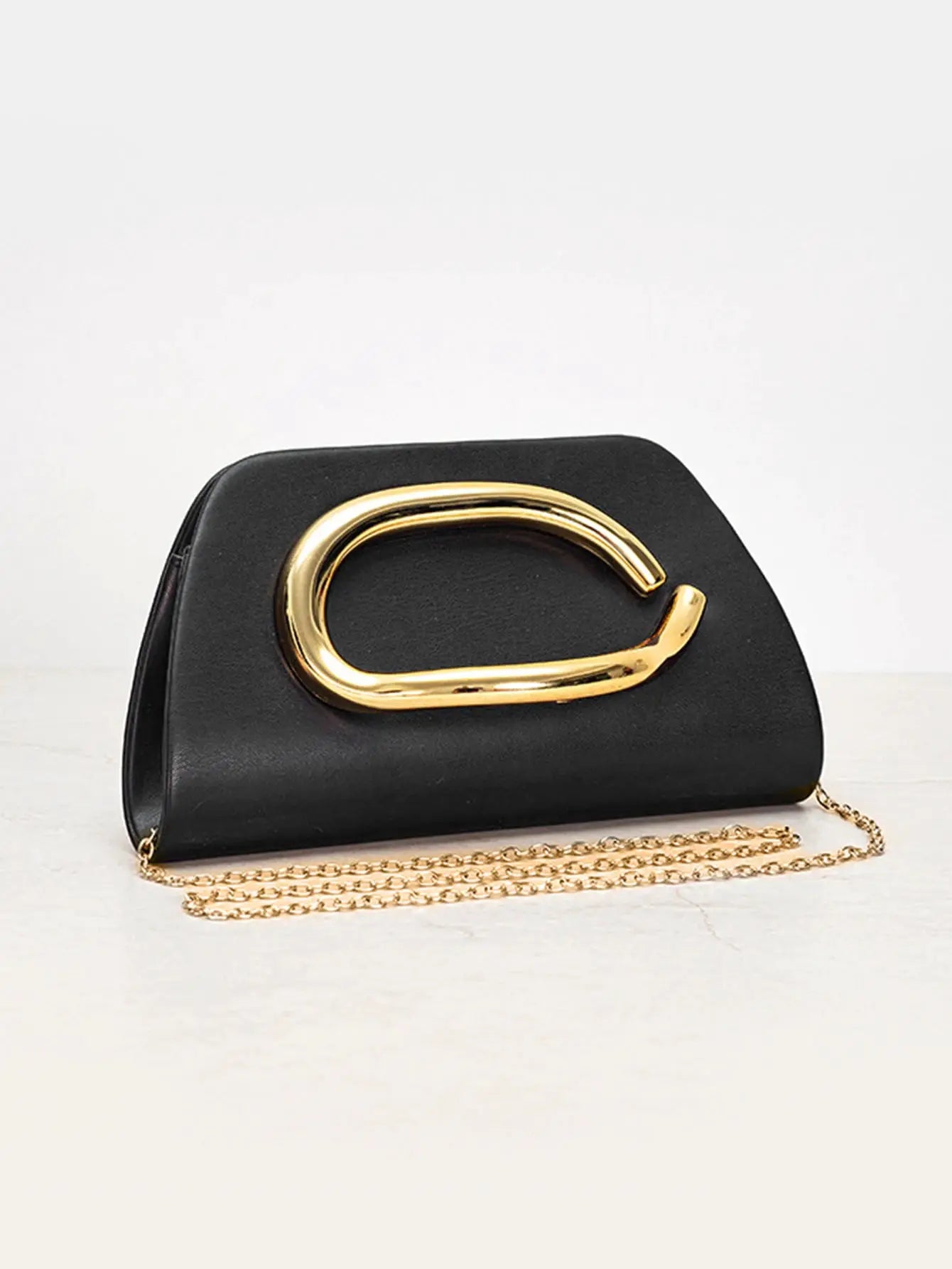 Box clutch in black with a large gold metal buckle and gold chain strap