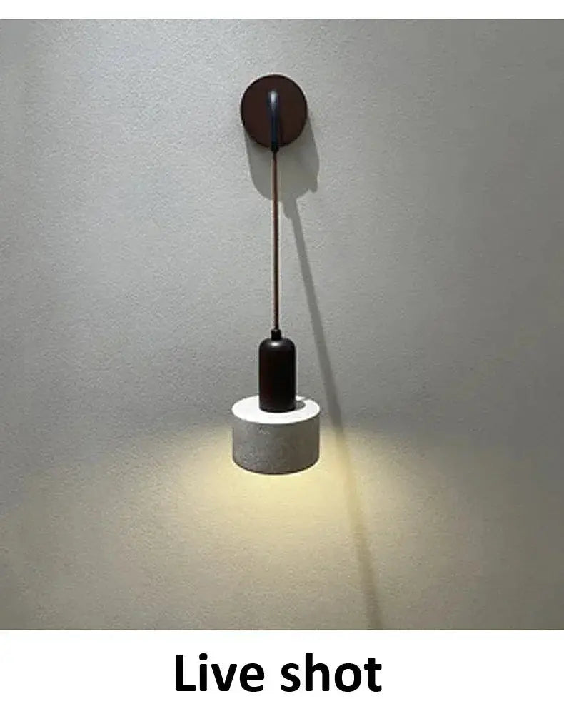Wall sconce lamp with peach wood-colored stem and concrete cylinder shade, warm LED light