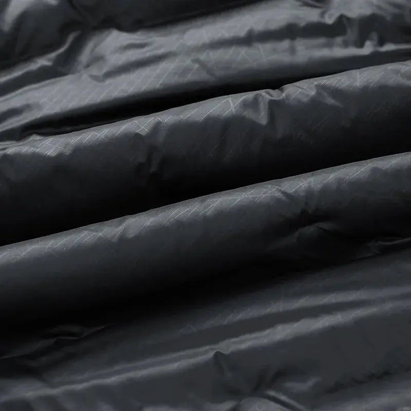 Men's down jacket fabric close-up in black nylon with subtle diagonal quilting.