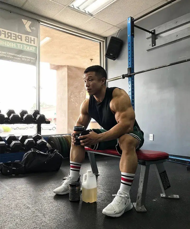 Men's basketball shorts in green mesh quick-dry fabric worn by a muscular man at the gym