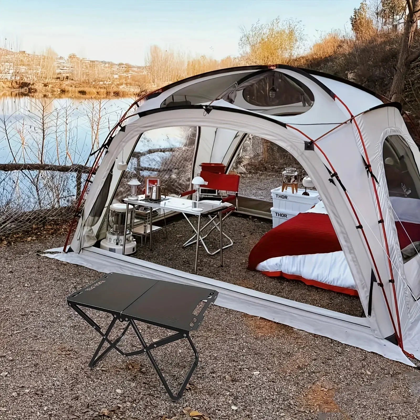 Portable folding camping table, stainless steel top with black frame for outdoor camping.