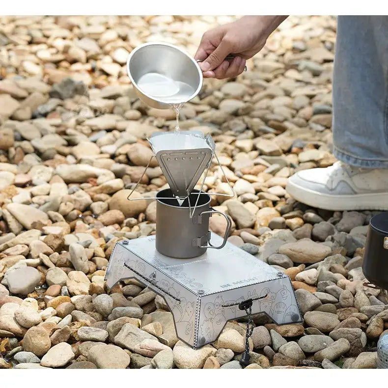 TINSOL ultralight folding mini table and camping stove, Simples Market, silver metal on rocky ground.