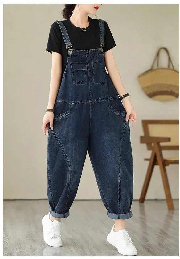 Blue denim overalls with suspenders and multiple pockets worn by a model in a black tee and white sneakers