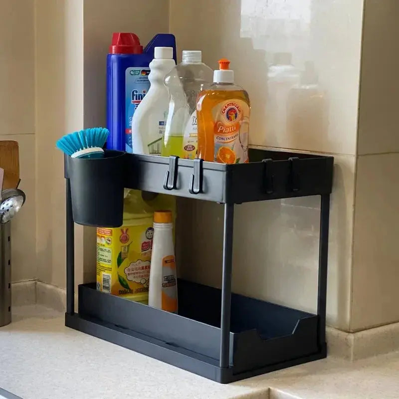 Multifunctional 2-tier under-sink sliding cabinet organizer in dark gray with hooks, holding cleaning supplies.