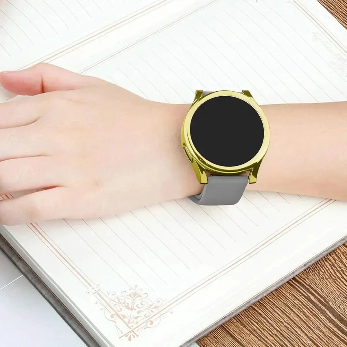 Gold smartwatch with black display and gray silicone strap on the wrist