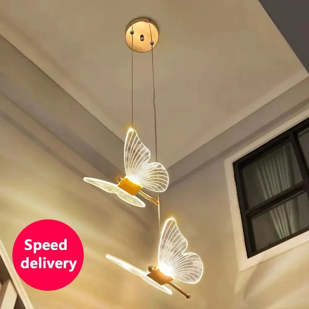 LED butterfly pendant lights (2) with glowing translucent wings and gold fixtures, hanging from ceiling.