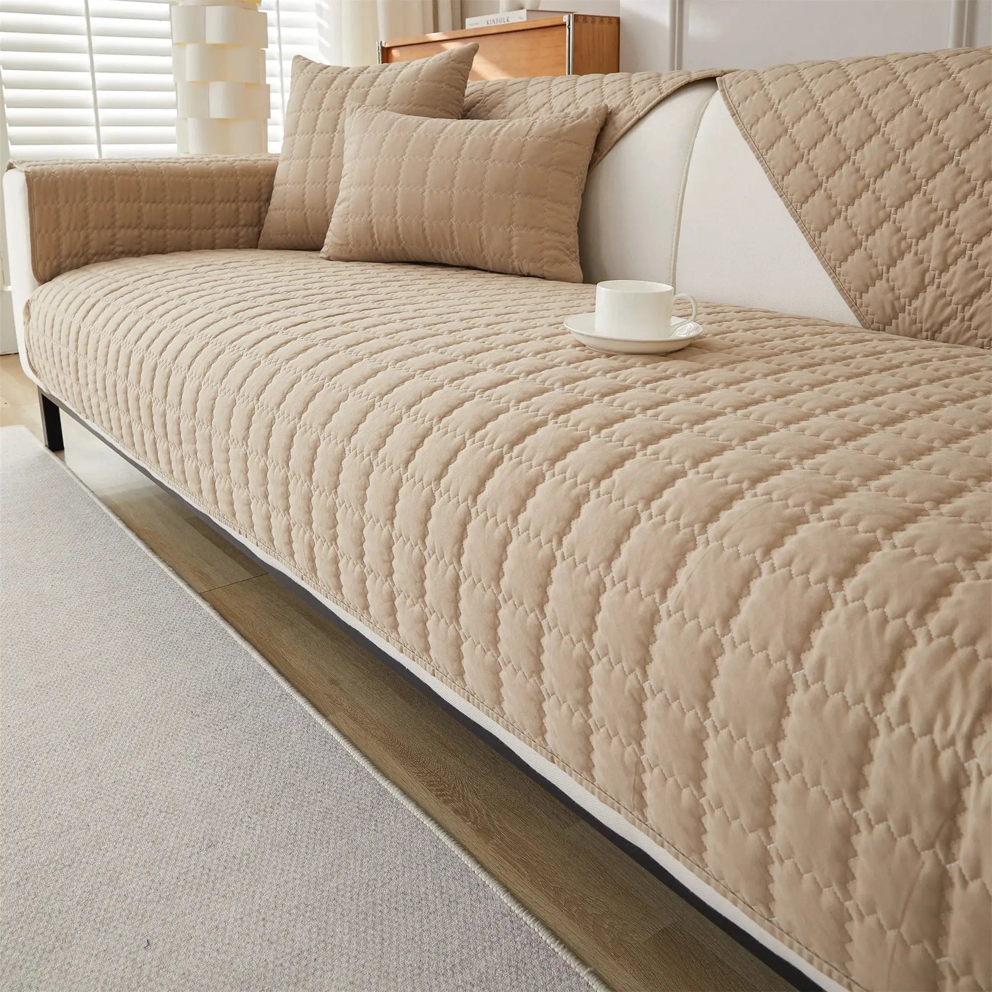 Sofa cover beige quilted with anti-slip backing on a living room sofa