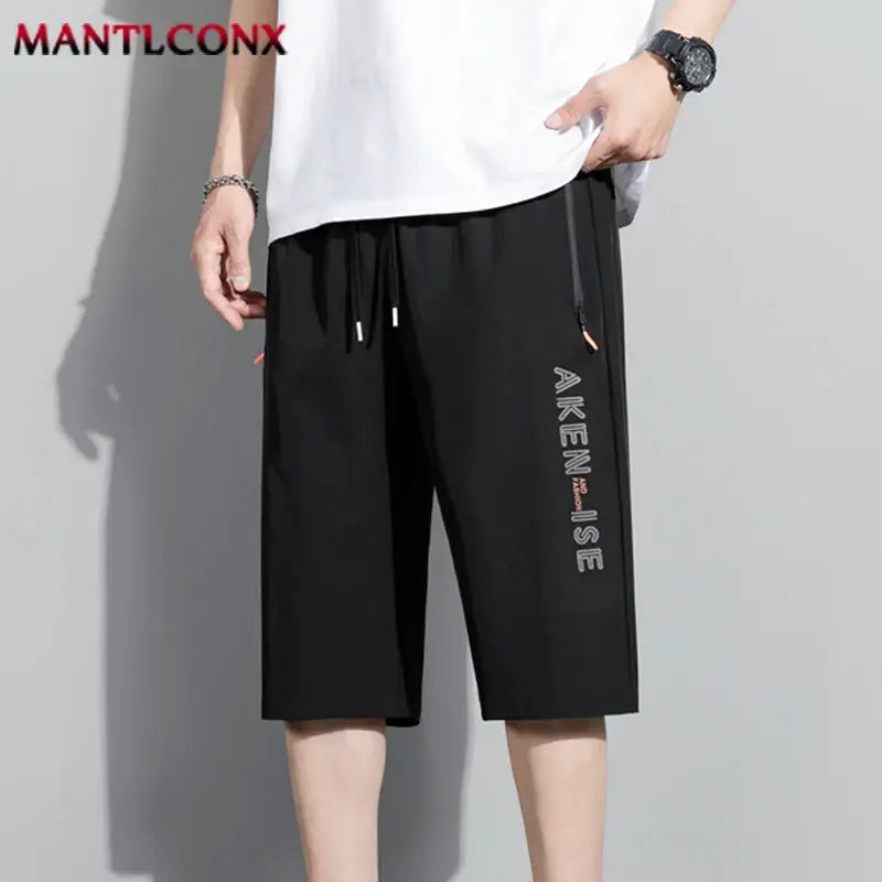 Men's black knee-length sports shorts with elastic waist and drawstring, breathable quick-dry fabric; MANTLCONX