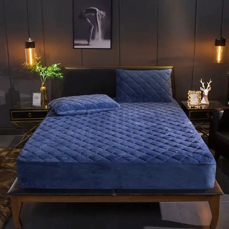 Quilted blue velvet mattress cover with plush padding on a bed with matching pillows
