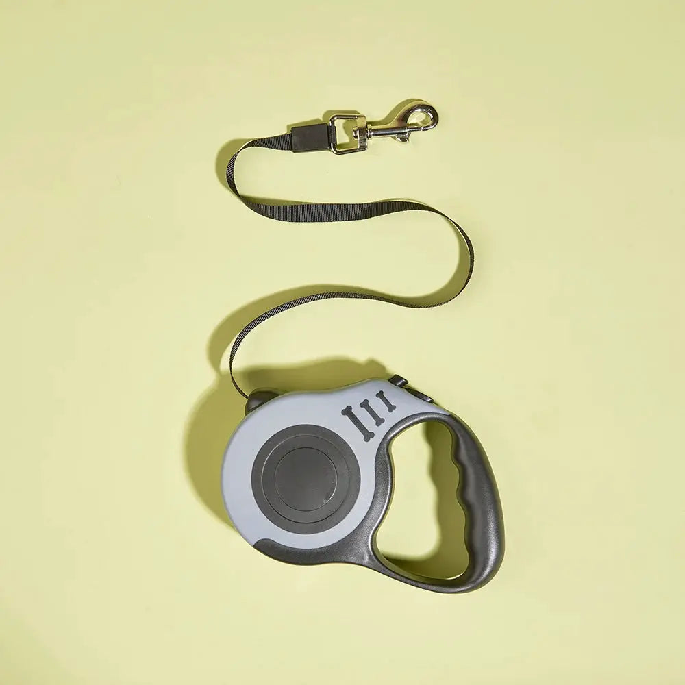 Retractable nylon dog leash with grey housing and ergonomic black handle, metal clip.