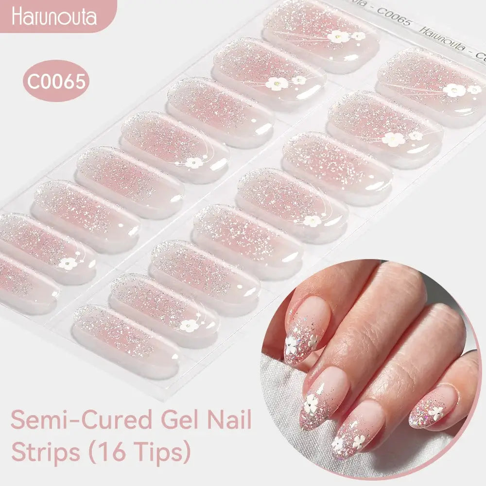 Gradient Auroras semi-cured gel nail strips by Harunouta, 16 pink-to-clear glitter tips with white flower accents