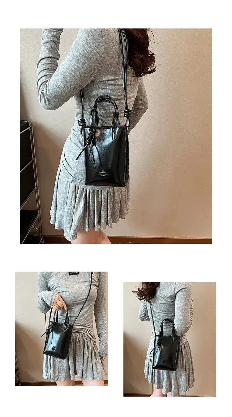 PU Leather mini crossbody bag in black with top handles and long strap, worn by a woman in a grey dress.
