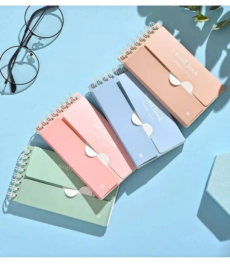 Six pastel word book notebooks with spiral bindings in assorted colors on a blue surface.